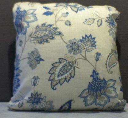 Cream cushion with blue floral pattern and leaves design.