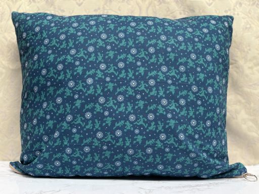Teal cushion covered with a floral pattern in white and shades of blue.