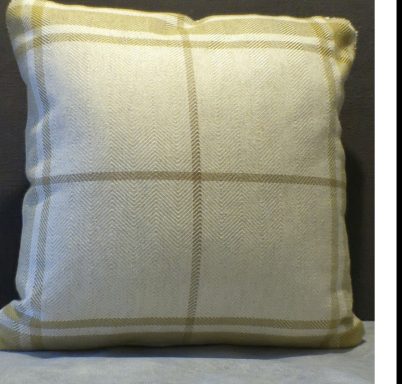 A cream cushion with a subtle yellow checked pattern.