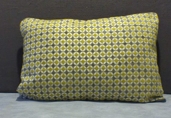 Rectangular cushion with a yellow and grey geometric pattern on a dark background.