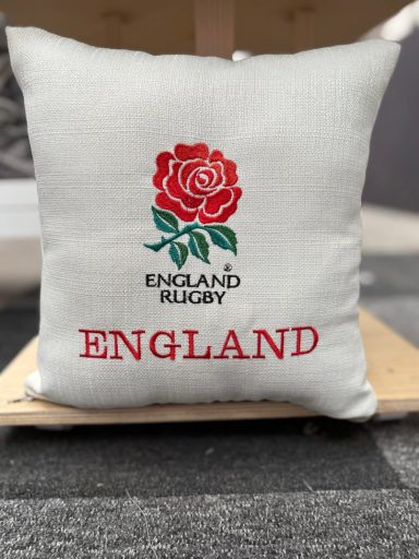White cushion with red rose and "England Rugby" text.