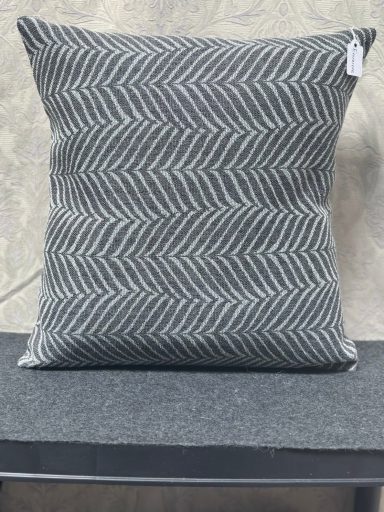 Grey chevron-patterned cushion on a dark grey surface.
