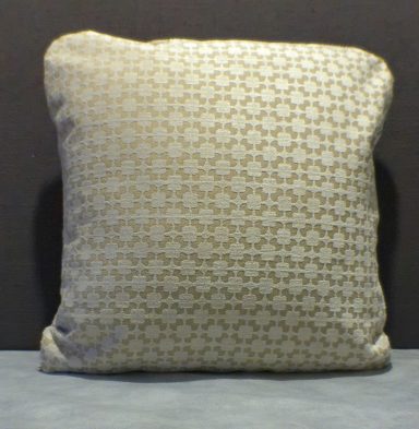 Beige cushion with a subtle geometric pattern on a grey background.