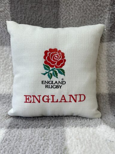 White cushion with red rose emblem and "England Rugby" text.