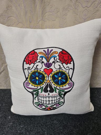 Decorative cushion featuring a colourful sugar skull design with roses and floral patterns.