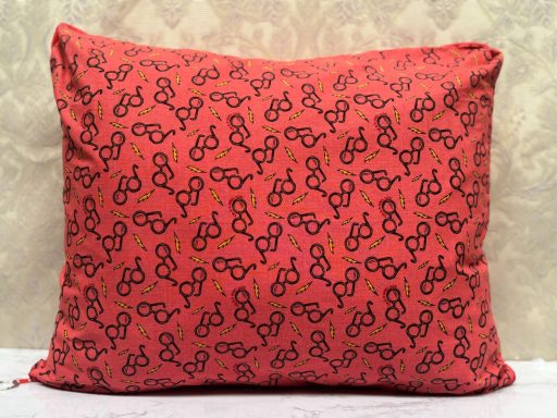 Red pillow with a repeated pattern of black eyeglasses design.