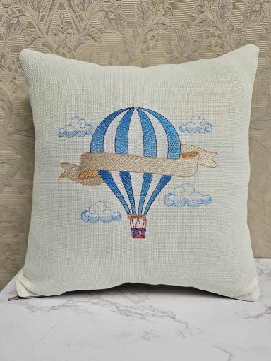 Embroidered cushion featuring a hot air balloon with a banner and clouds.