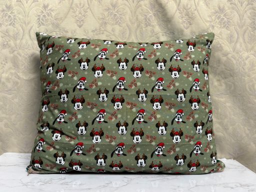 A green pillow featuring a pattern of dogs wearing red hats and holding bones.