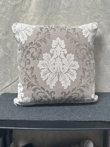 Square decorative cushion with an ornate grey and white floral pattern.