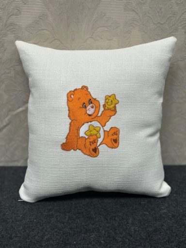 Cushion featuring an orange bear holding a cookie, set against a neutral background.