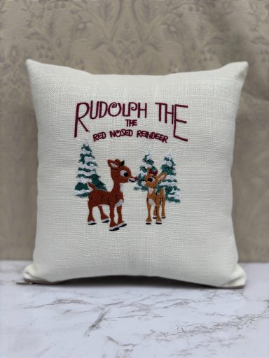 Decorative cushion featuring Rudolph the Red-Nosed Reindeer and trees.
