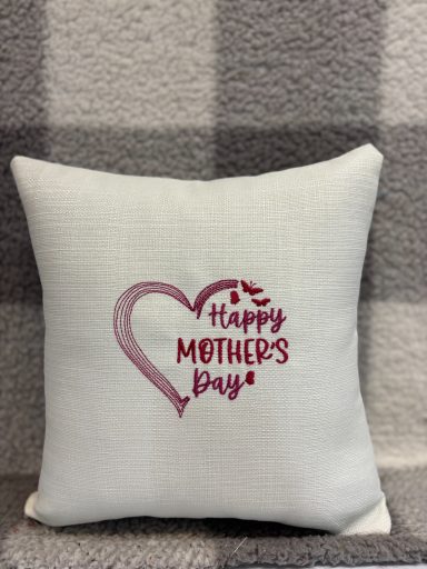White cushion with "Happy Mother's Day" in a pink heart design.