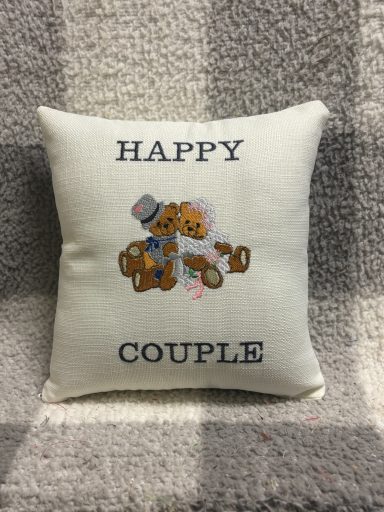 A decorative cushion with the text "HAPPY COUPLE" and cartoon bears.