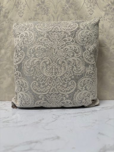 A textured decorative cushion with a patterned design against a light background.