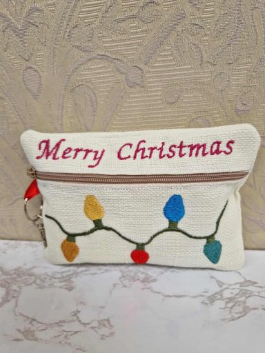 White pouch with "Merry Christmas" and decorative colourful Christmas lights.