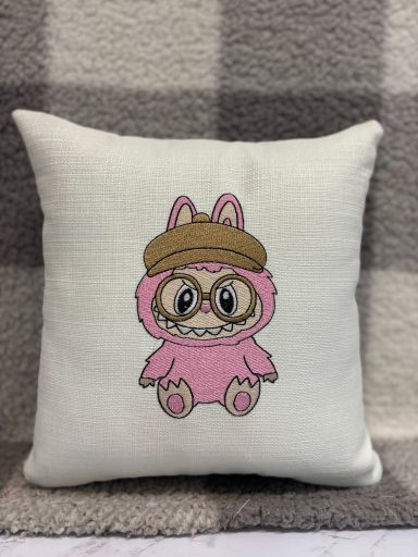 A plush cushion featuring a cute pink bunny character wearing a brown hat.