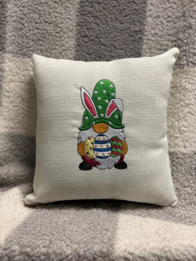 A decorative cushion featuring a cartoon rabbit with a green hat and Easter eggs.