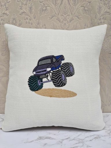 A blue monster truck jumping over a sandy surface, featured on a cushion.