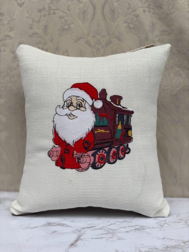 A decorative cushion featuring Santa Claus beside a traditional steam train.