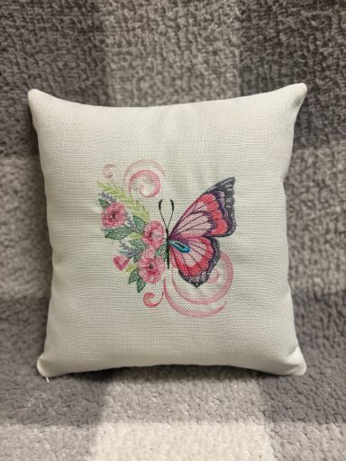 Light green cushion with a butterfly and floral embroidery design.