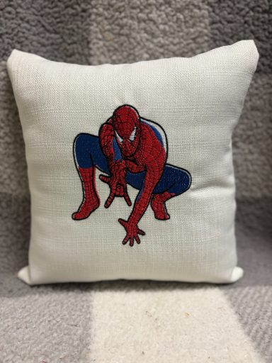 A cushion featuring an embroidered Spider-Man in a crouching pose.