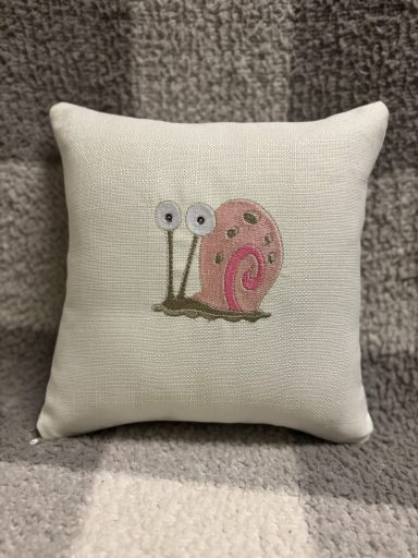 Gary Snail A decorative cushion featuring a pink snail with large eyes and a swirled shell.