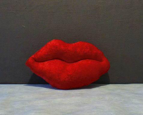 Red plush lips on a grey background.