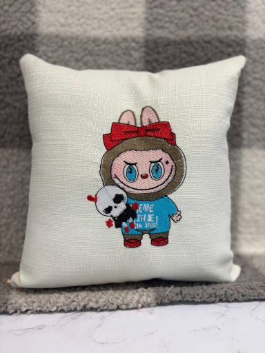 A decorative cushion featuring a character with a bunny hat and holding a panda toy.