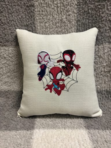 Spidey Mates Cushion featuring three Spider-Man characters on a textured cream background.