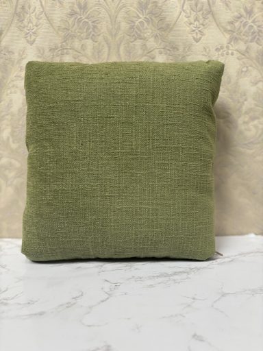 Square green cushion placed on a marble surface with a textured background.