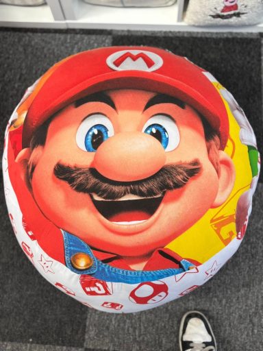 Round cushion featuring a smiling Mario character from video games.