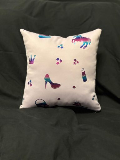 Pillow with a pattern of high heels, lipsticks, and small decorative elements on a light background.