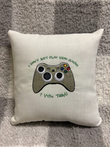 Cushion with a video game controller design and the text "I don't play video games, I own them."