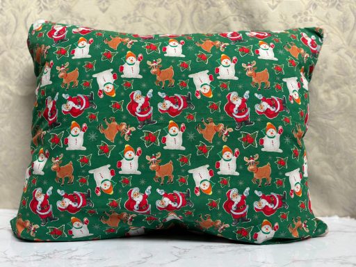 Green decorative pillow with festive snowmen, reindeer, and Christmas ornaments.