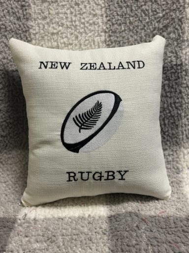 Cushion featuring "New Zealand Rugby" and a rugby ball emblem.
