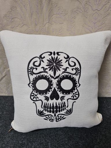 White cushion featuring a decorative black skull design with intricate patterns.