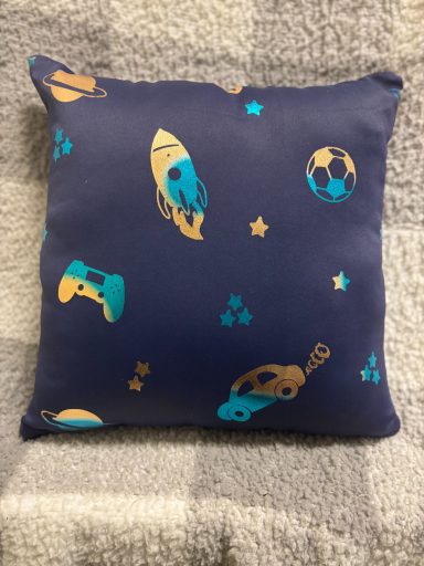 Navy cushion featuring gaming controllers, footballs, and stars in bright colours.