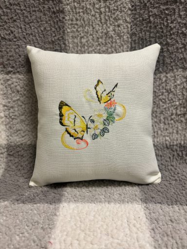 Decorative cushion featuring embroidered butterflies and floral elements.
