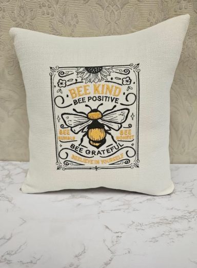 Square cushion featuring a bee illustration and the text "Be Kind. Bee Positive."