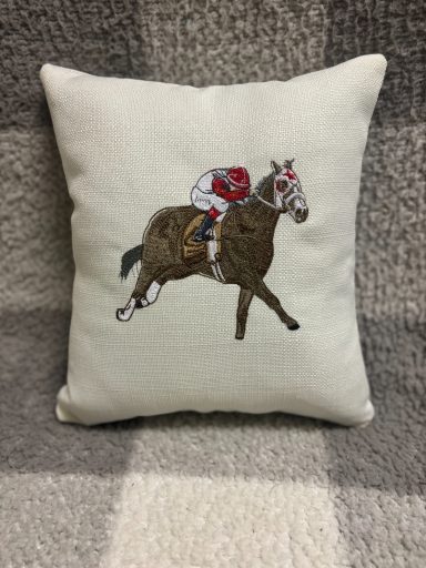 Cushion featuring an embroidered horse and jockey in motion.