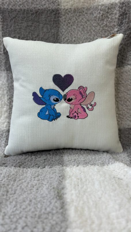 Two cute cartoon creatures, one blue and one pink, share a heart.