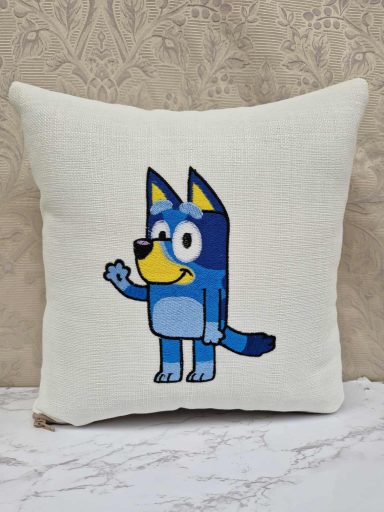 Cartoon blue dog character with a friendly wave on a white cushion.