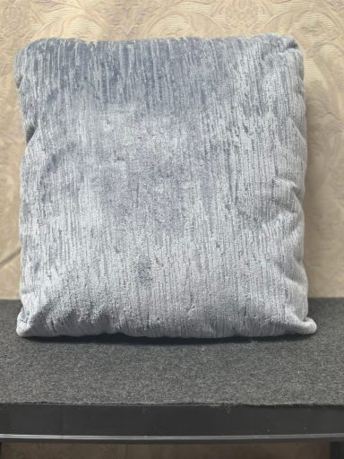 Soft, square, grey cushion placed on a dark surface.