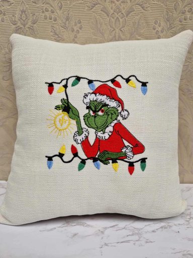 A decorative cushion featuring the Grinch with Christmas lights.