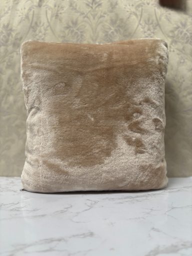Plain beige cushion on a marble surface.