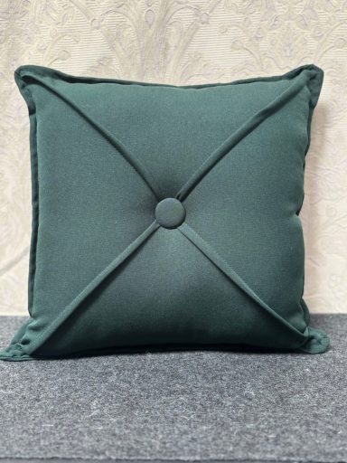 Green decorative cushion with a button in the centre and stitched corners.