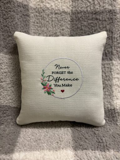 Decorative cushion with the text "There is no greater difference" and floral design.