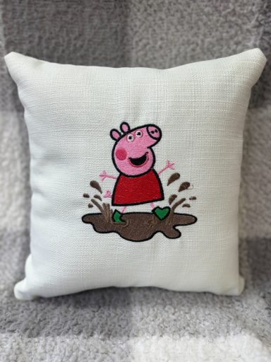 Cushion featuring Peppa Pig jumping in muddy puddles, smiling with a red dress.