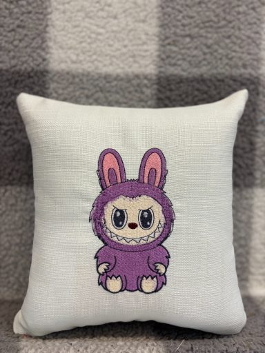 Cute plush cushion featuring a bunny character in a purple outfit.