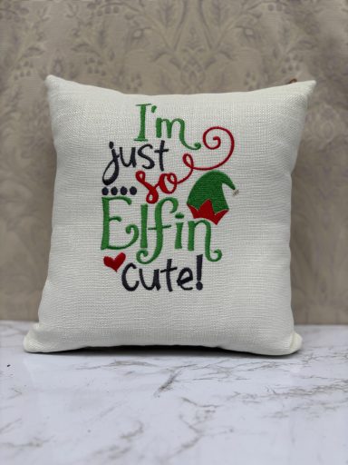 A decorative cushion with the text "I'm just Effin cute!" in festive colours and designs.